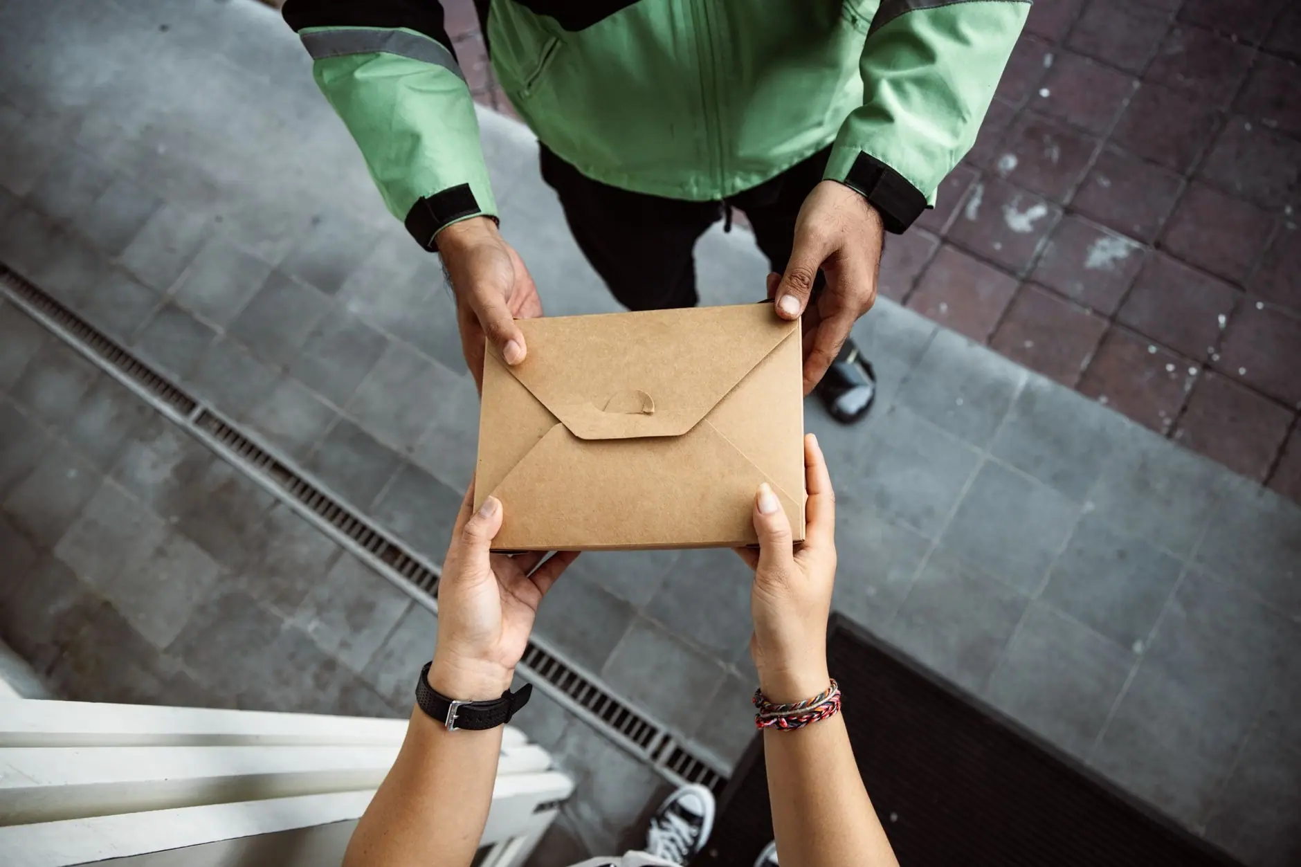 Enveloppe kraft remise de la main à la main, sur un trottoir