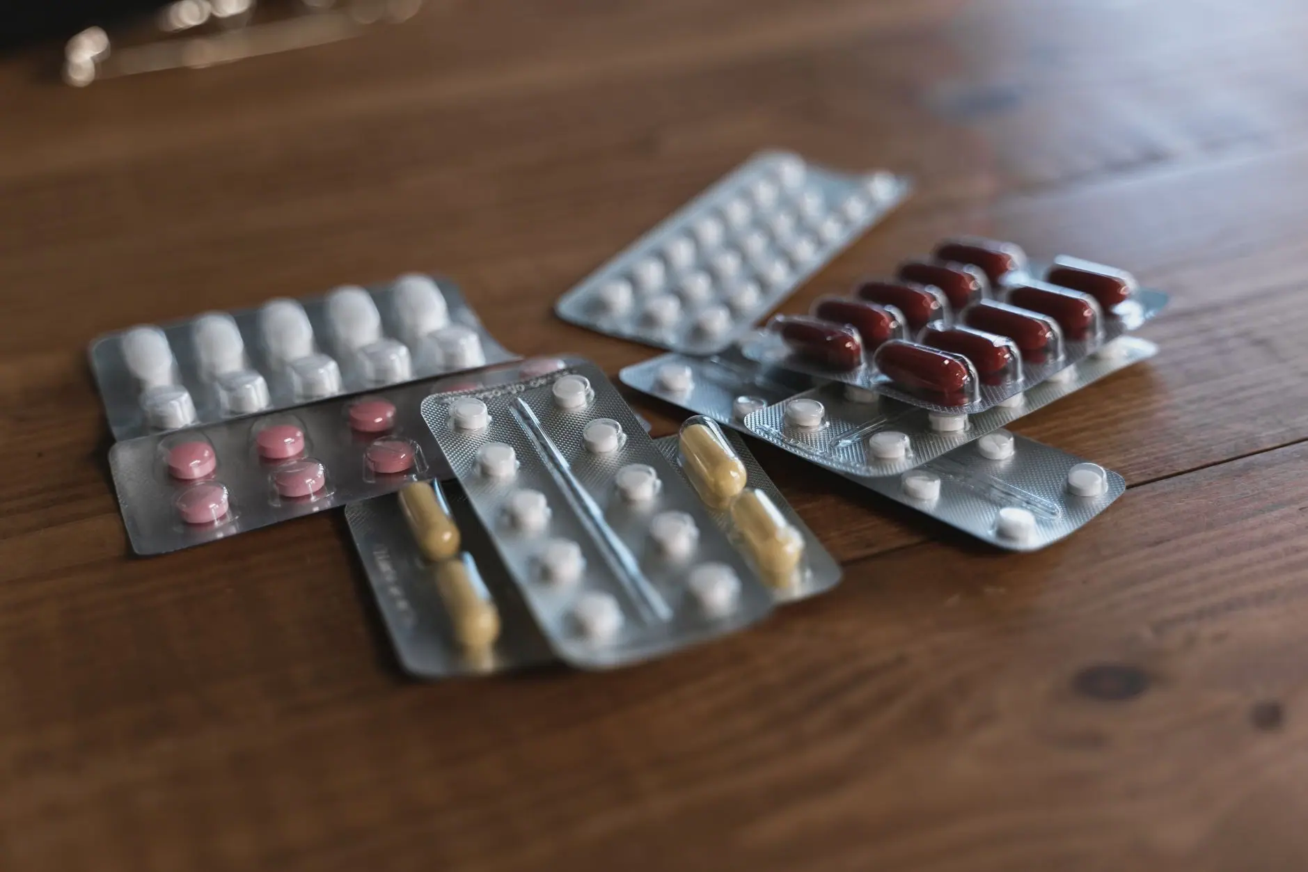 Plaquettes de médicaments de différentes couleurs posées sur une table en bois