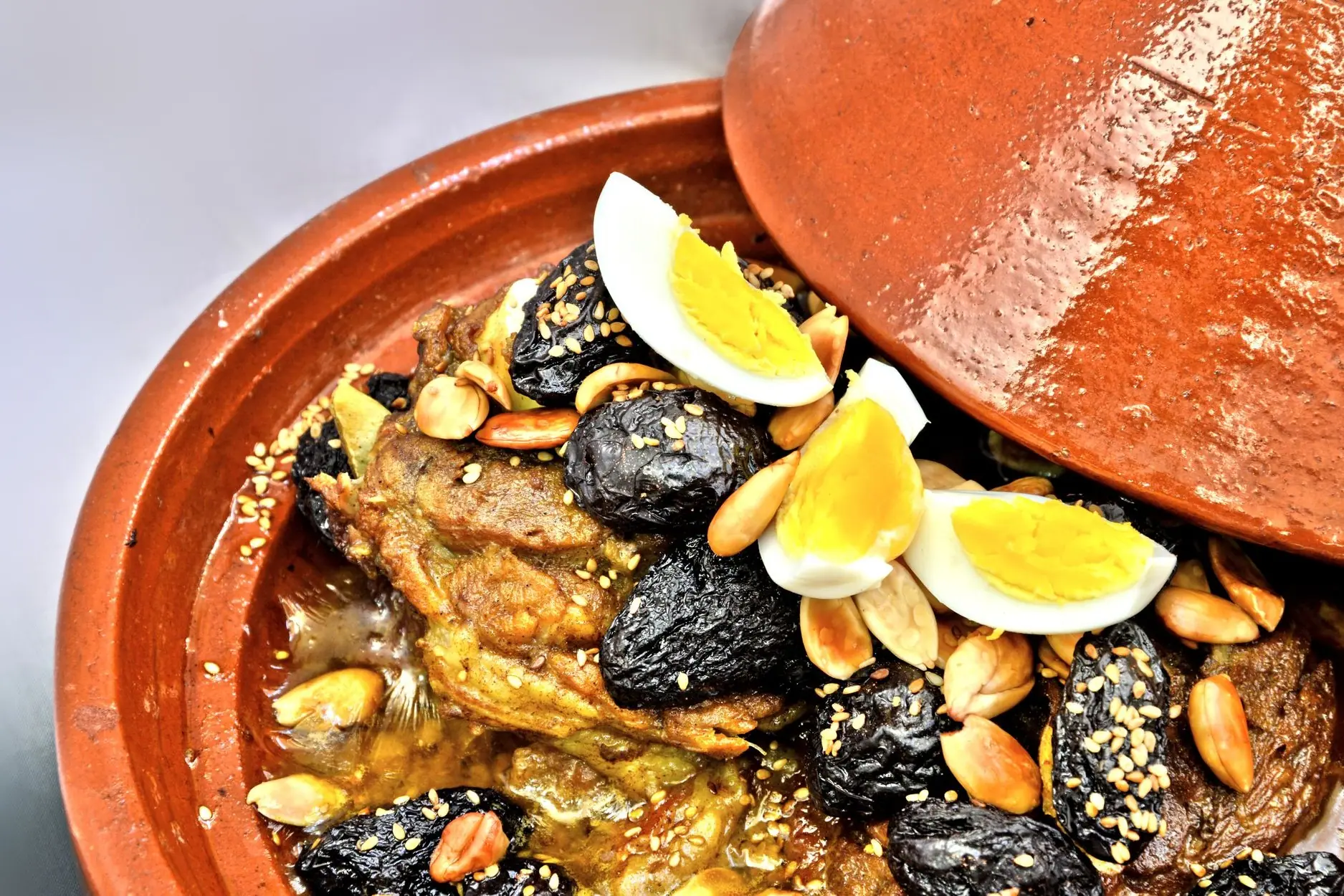 Tajine d'agneau aux pruneaux, amandes et œufs, servi dans son plat en terre